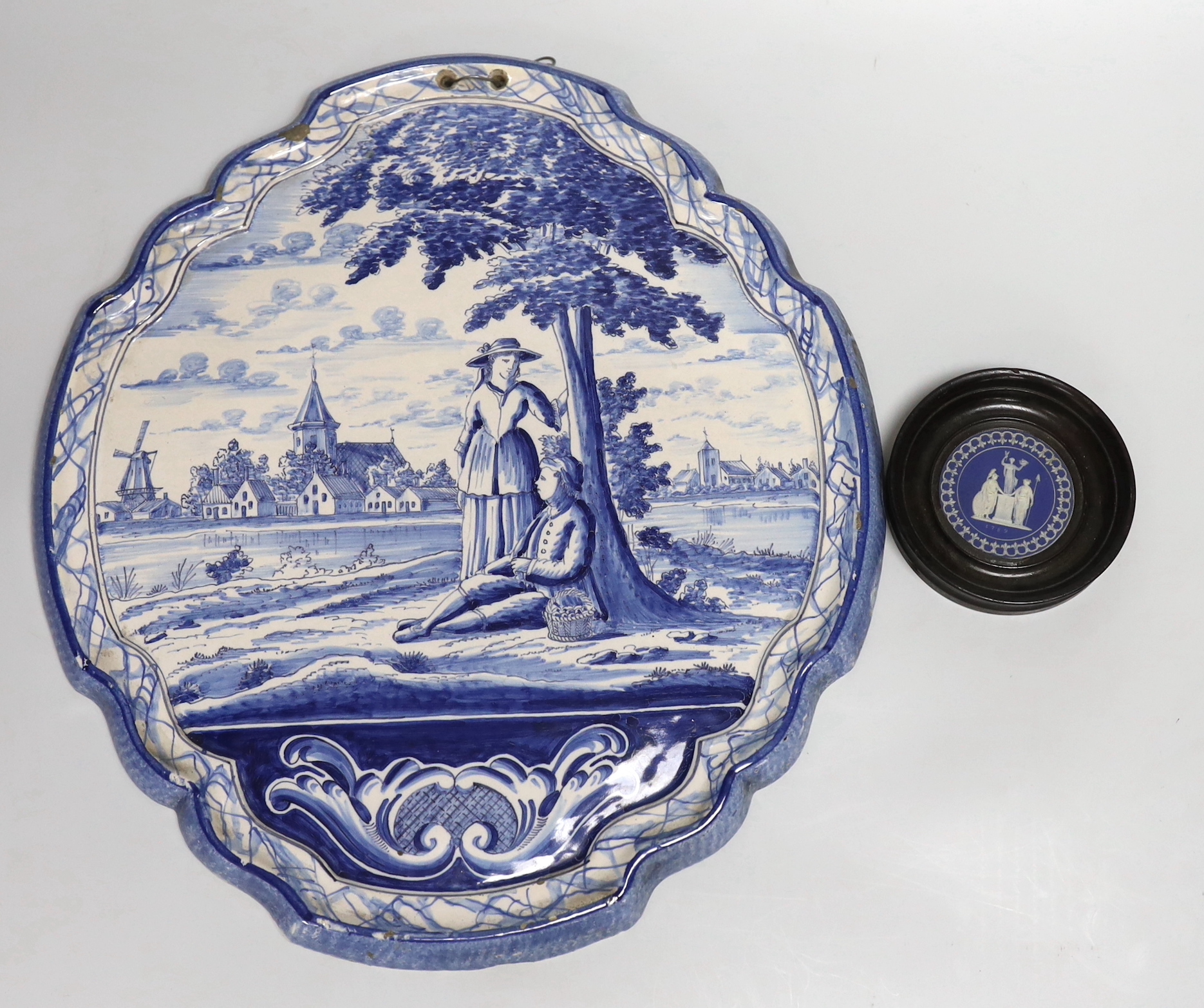 A framed Wedgwood jasperware circular plaque dated 1789 and a delft blue and white example, the largest 37cm high